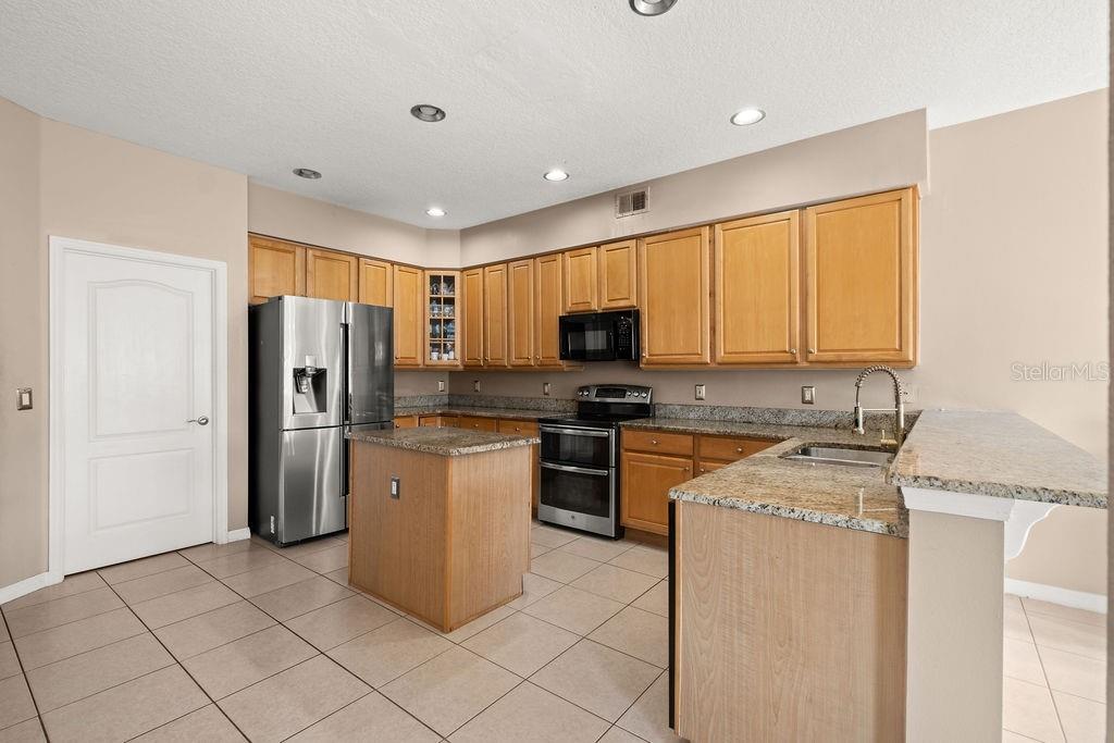 1349 Castleport Road Winter Garden, FL 34787 - Photo 14 of 40 a kitchen with stainless steel appliances granite countertop a refrigerator stove microwave and sink