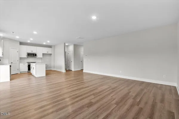 a view of kitchen with kitchen island wooden floor stainless steel appliances and cabinets