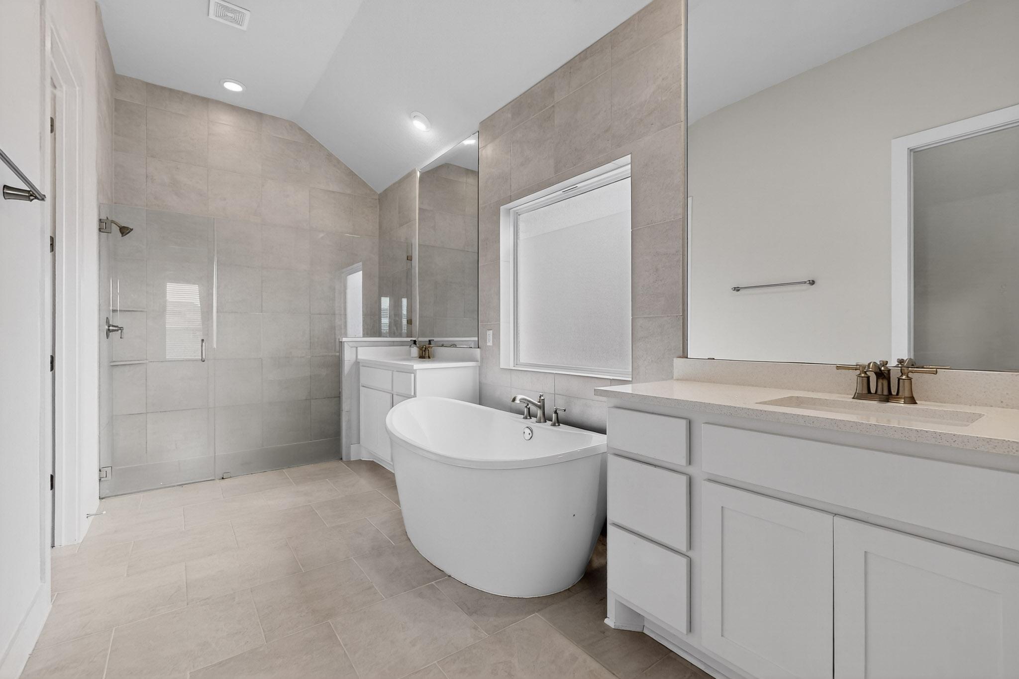 20912 Carries Ranch Road Pflugerville, TX 78660 - Photo 9 of 20 High vaulted ceilings and tile finishes elevate this modern primary bath with a freestanding tub.