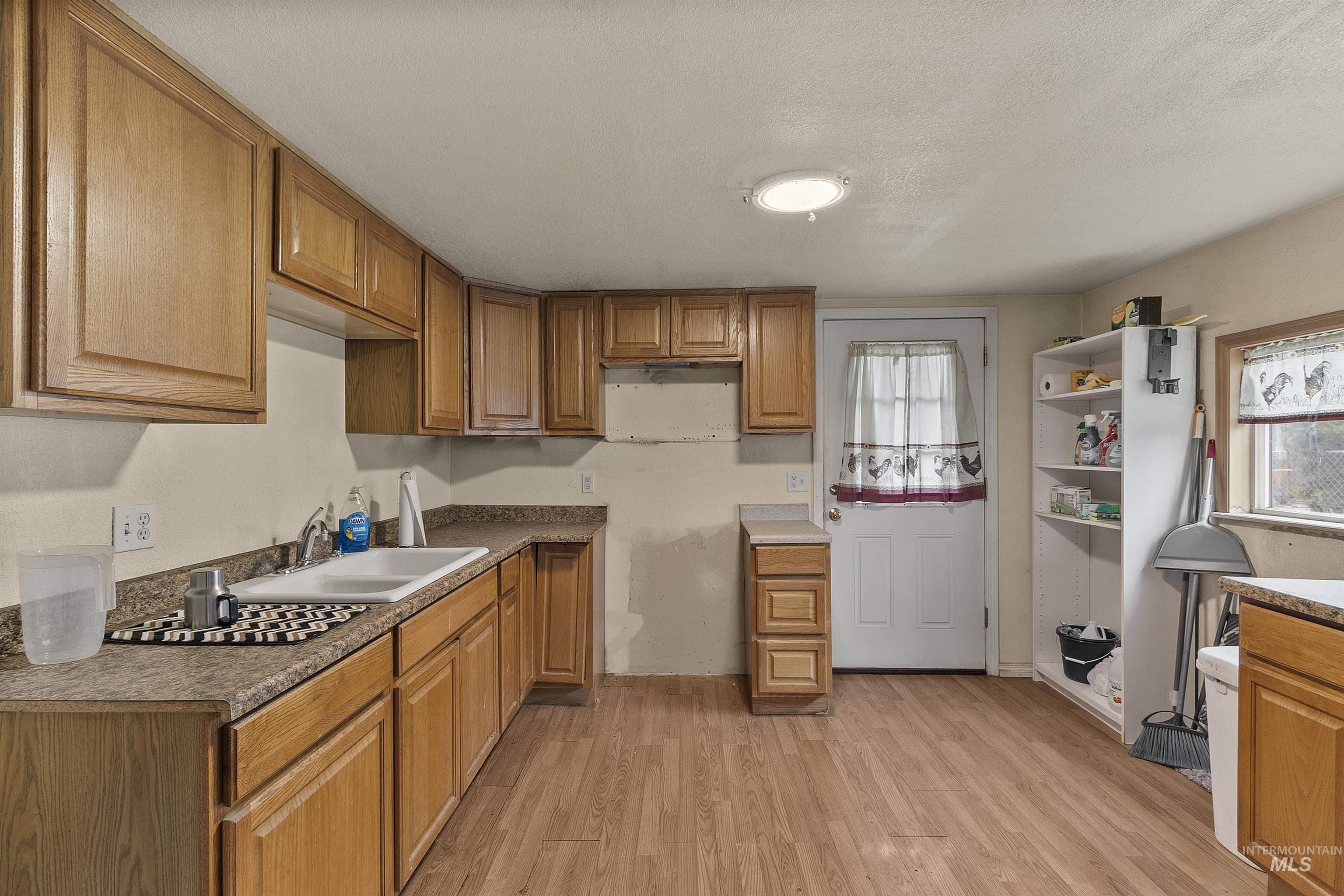 721 9th Street Clarkston, WA 99403 - Photo 14 of 39 Kitchen featuring light wood-style floors, wood finish cabinetry, a textured ceiling, and open shelves