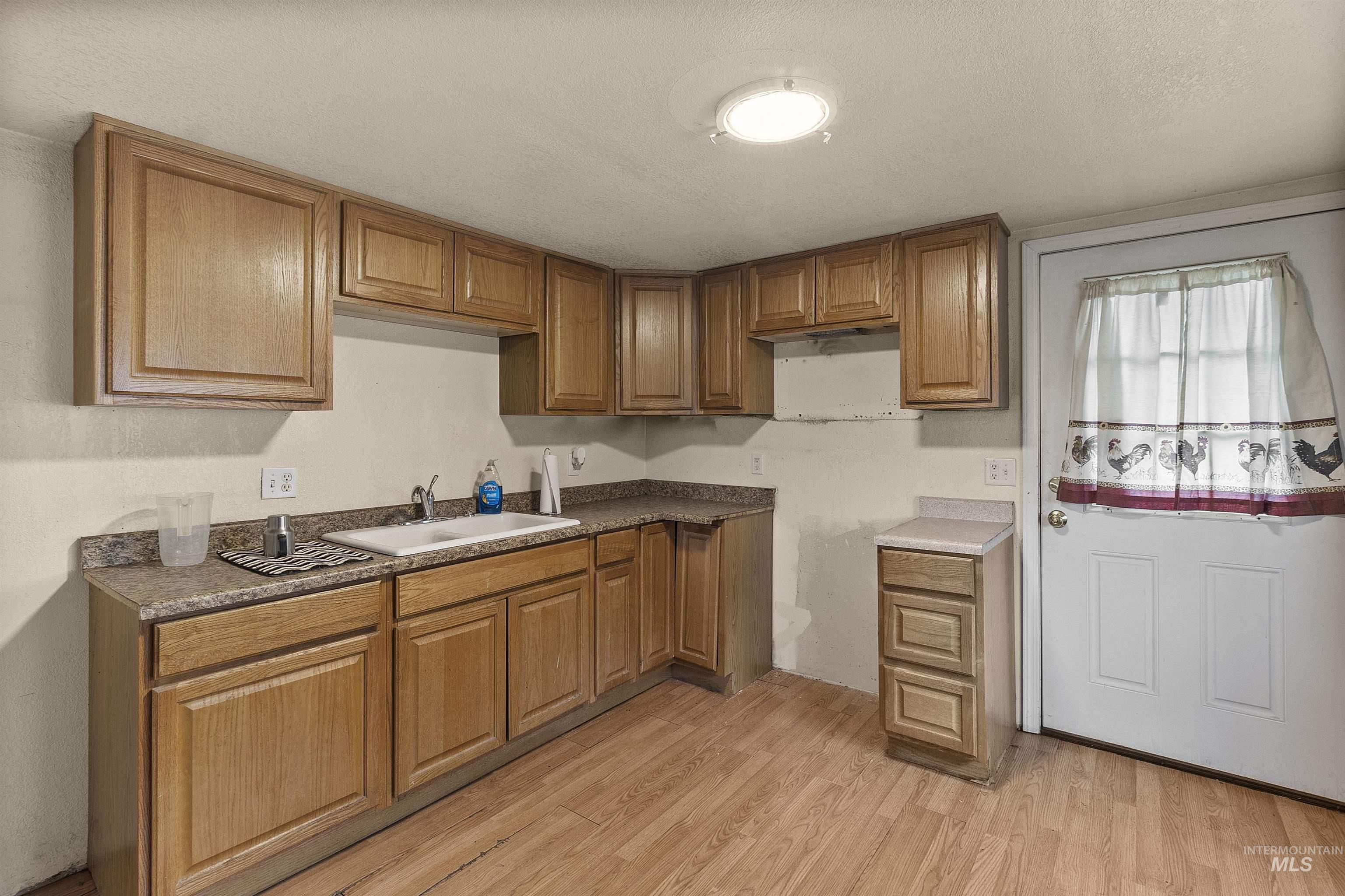 721 9th Street Clarkston, WA 99403 - Photo 16 of 39 Kitchen with light wood finished floors, wood finish cabinets, and a textured ceiling