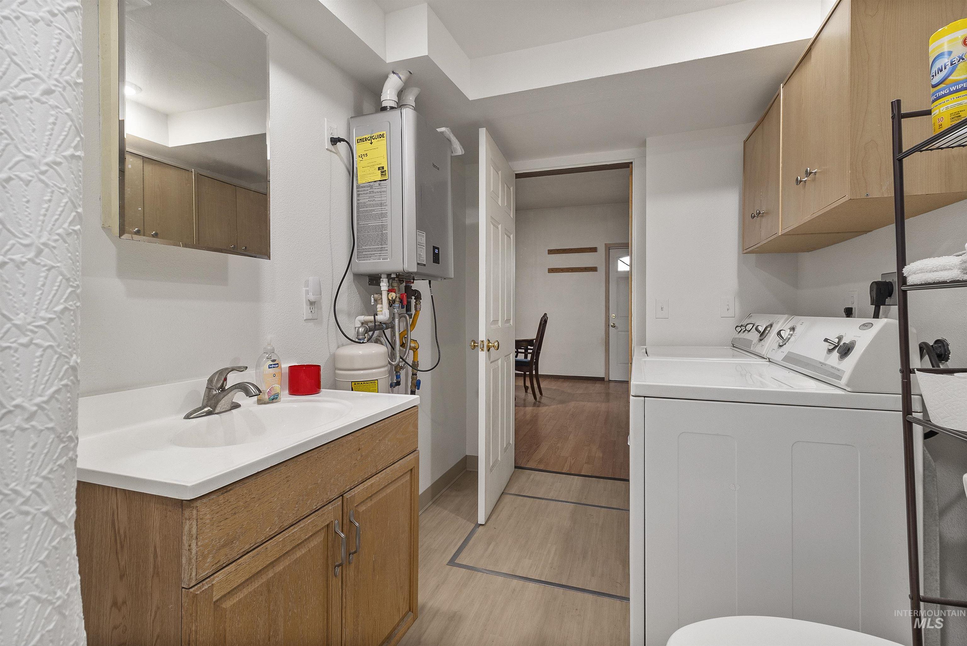 721 9th Street Clarkston, WA 99403 - Photo 24 of 39 Laundry room featuring separate washer and dryer, tankless water heater, and cabinet space