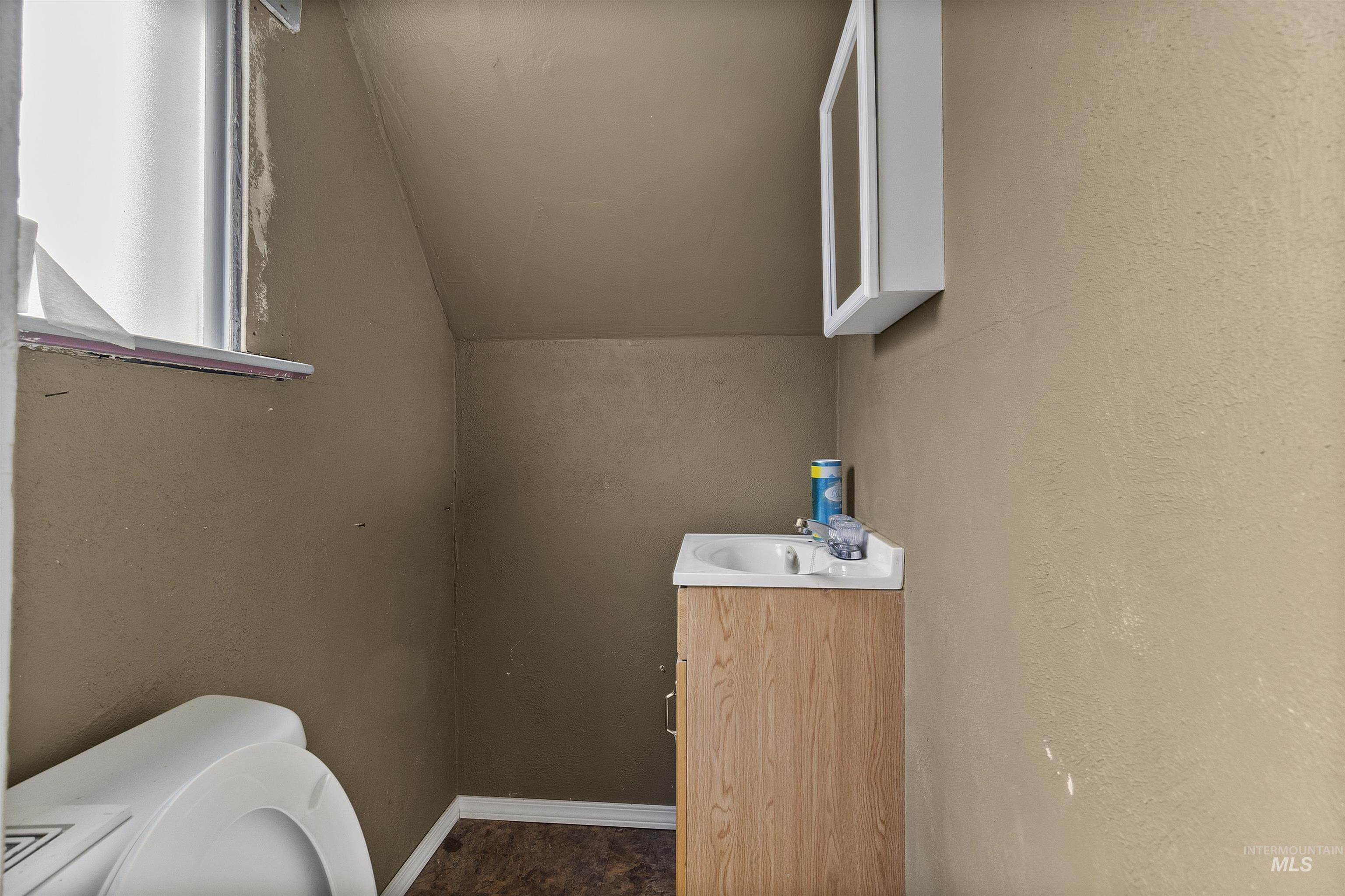 721 9th Street Clarkston, WA 99403 - Photo 32 of 39 Half bathroom featuring vanity, vaulted ceiling, and a textured wall