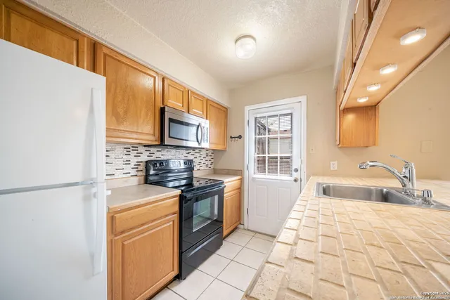 a kitchen with stainless steel appliances granite countertop a stove a sink and a refrigerator