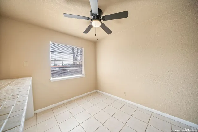 an empty room with windows and fan