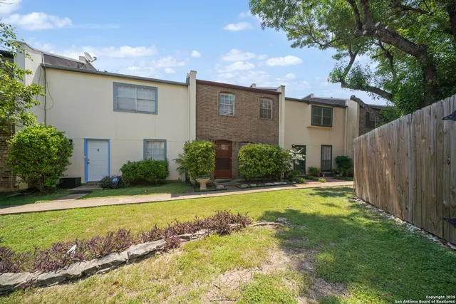 a view of a house with a yard and a tree