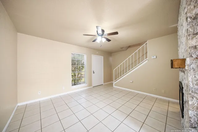 a view of an empty room with chandelier fan