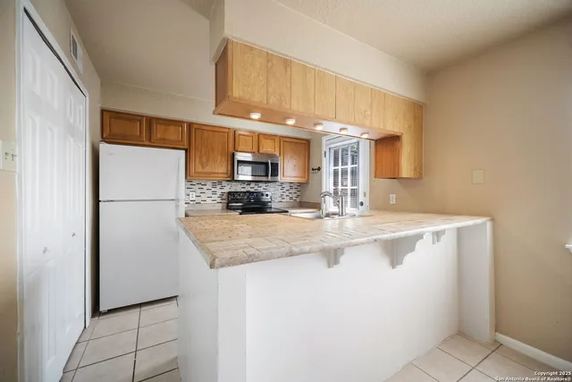 a kitchen with stainless steel appliances granite countertop a refrigerator a stove a sink and a refrigerator