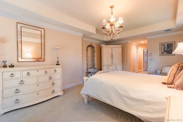a spacious bedroom with a bed a chandelier and dresser