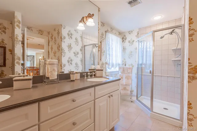 a bathroom with a double vanity sink mirror and shower