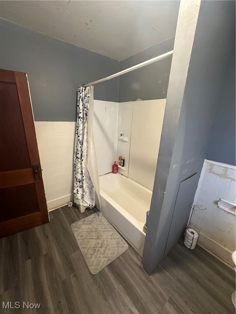 757 Noah Avenue Akron, OH 44320 - Photo 12 of 16 Bathroom with shower / bathtub combination with curtain, a wainscoted wall, tile walls, and wood finished floors