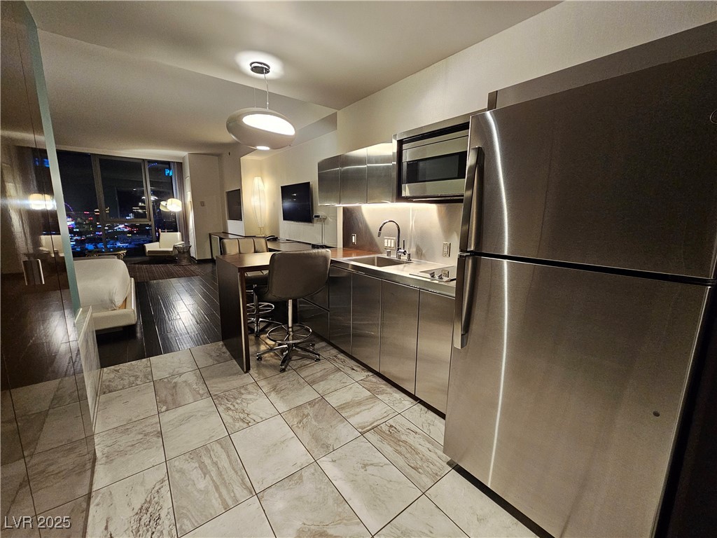 4381 West Flamingo Road, Unit 1806 Las Vegas, NV 89103 - Photo 10 of 12 Kitchen featuring stainless steel appliances, pendant lighting, light countertops, a kitchen breakfast bar, and modern cabinets
