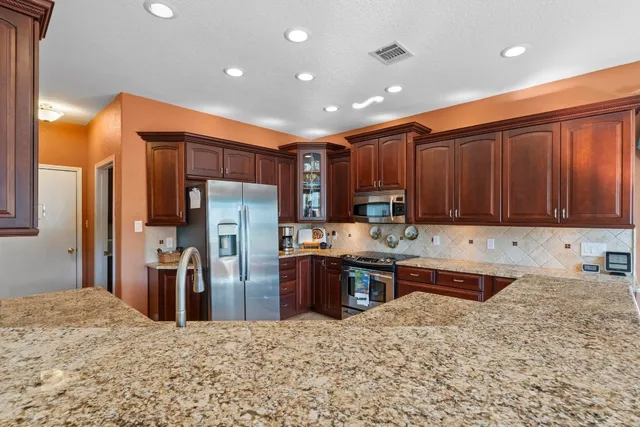a kitchen with stainless steel appliances kitchen island granite countertop a refrigerator and a sink