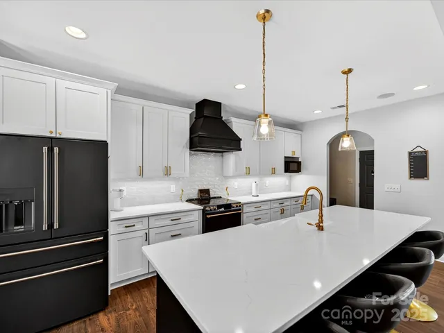 a kitchen with stainless steel appliances a sink a stove a refrigerator a dining table and chairs