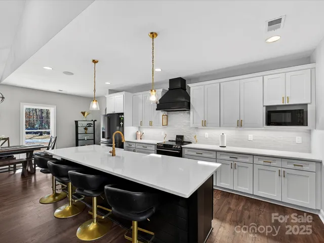 a kitchen with a sink a stove and chairs with wooden floor