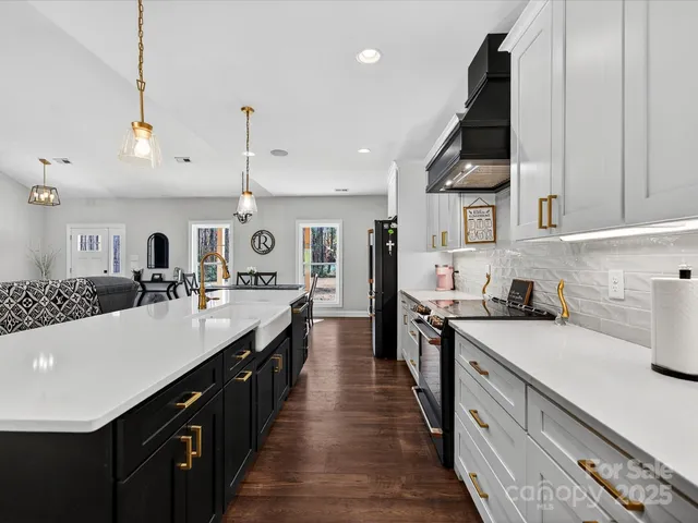 a large kitchen with stainless steel appliances a sink dishwasher a stove and a refrigerator with wooden floor