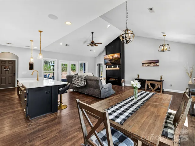 a living room with couches chairs and kitchen view with wooden floor