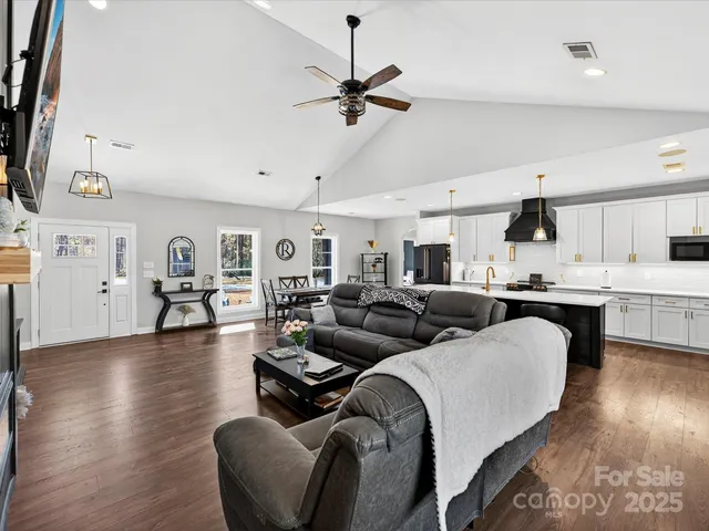 a living room with furniture kitchen view and a wooden floor