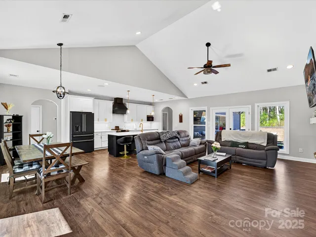 a living room with furniture kitchen view and a wooden floor