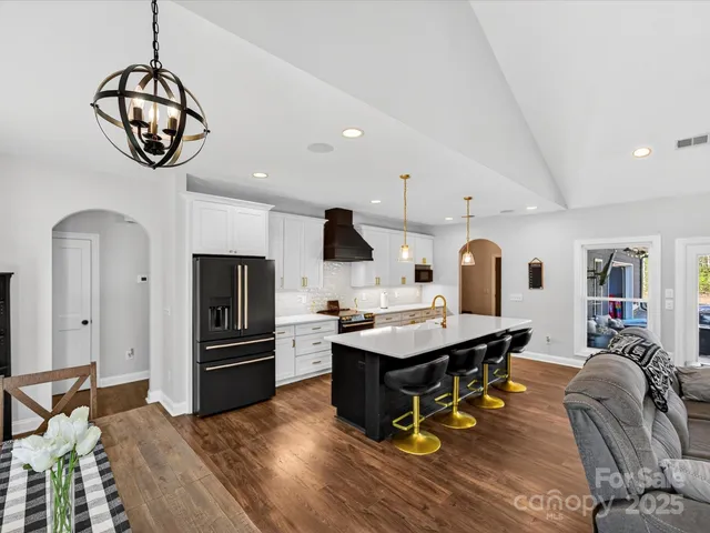 a kitchen with stainless steel appliances kitchen island granite countertop a table chairs in it and wooden floors