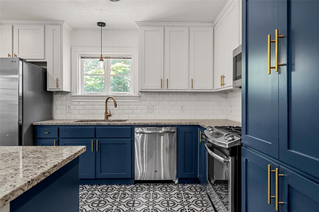 3225 Windsor Avenue Waco, TX 76708 - Photo 9 of 25 Kitchen featuring two-tone cabinetry with gold-tone hardware, granite countertops, patterned floor tiles, stainless steel appliances, and subway tile backsplash