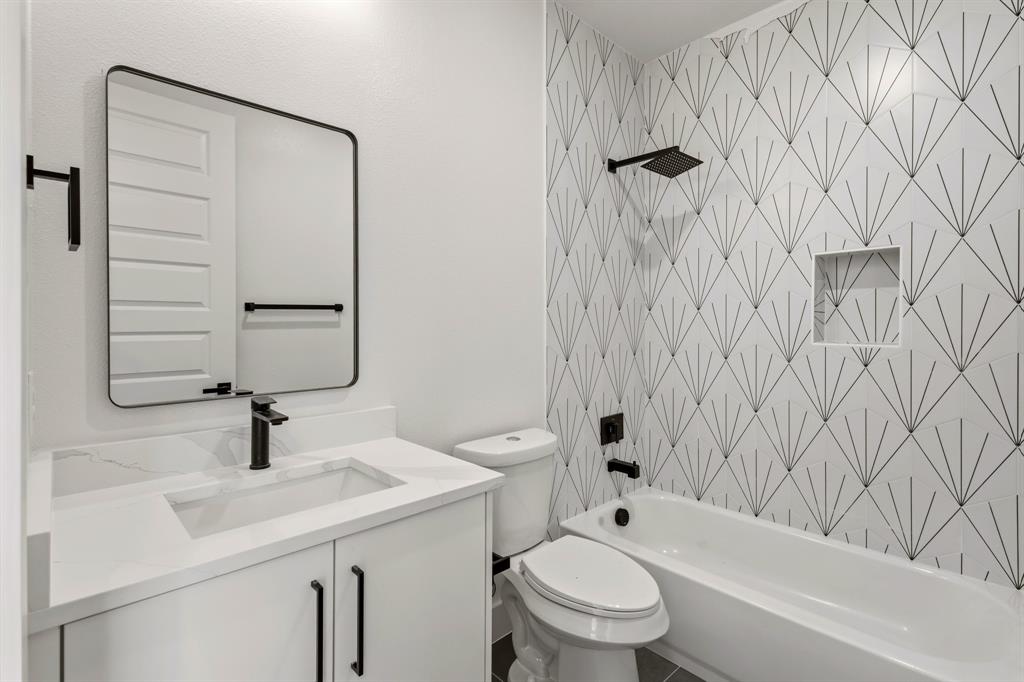 415 North Patton Avenue Dallas, TX 75203 - Photo 13 of 20 Bathroom featuring a white vanity with a rectangular sink, a black framed mirror, and a bathtub with a tiled surround