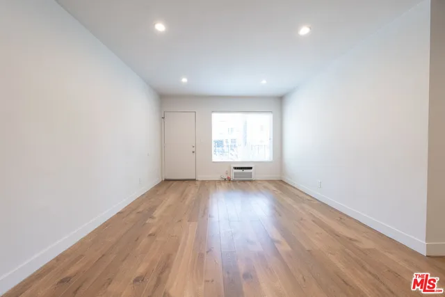 an empty room with wooden floor and window