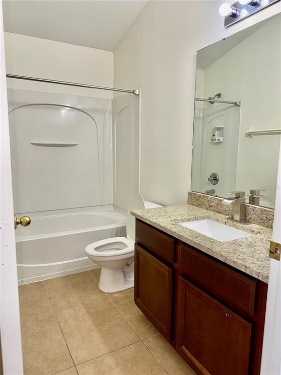 6404 South Goldenrod Road, Unit 2A Orlando, FL 32822 - Photo 15 of 40 a bathroom with a granite countertop toilet a sink and a bathtub
