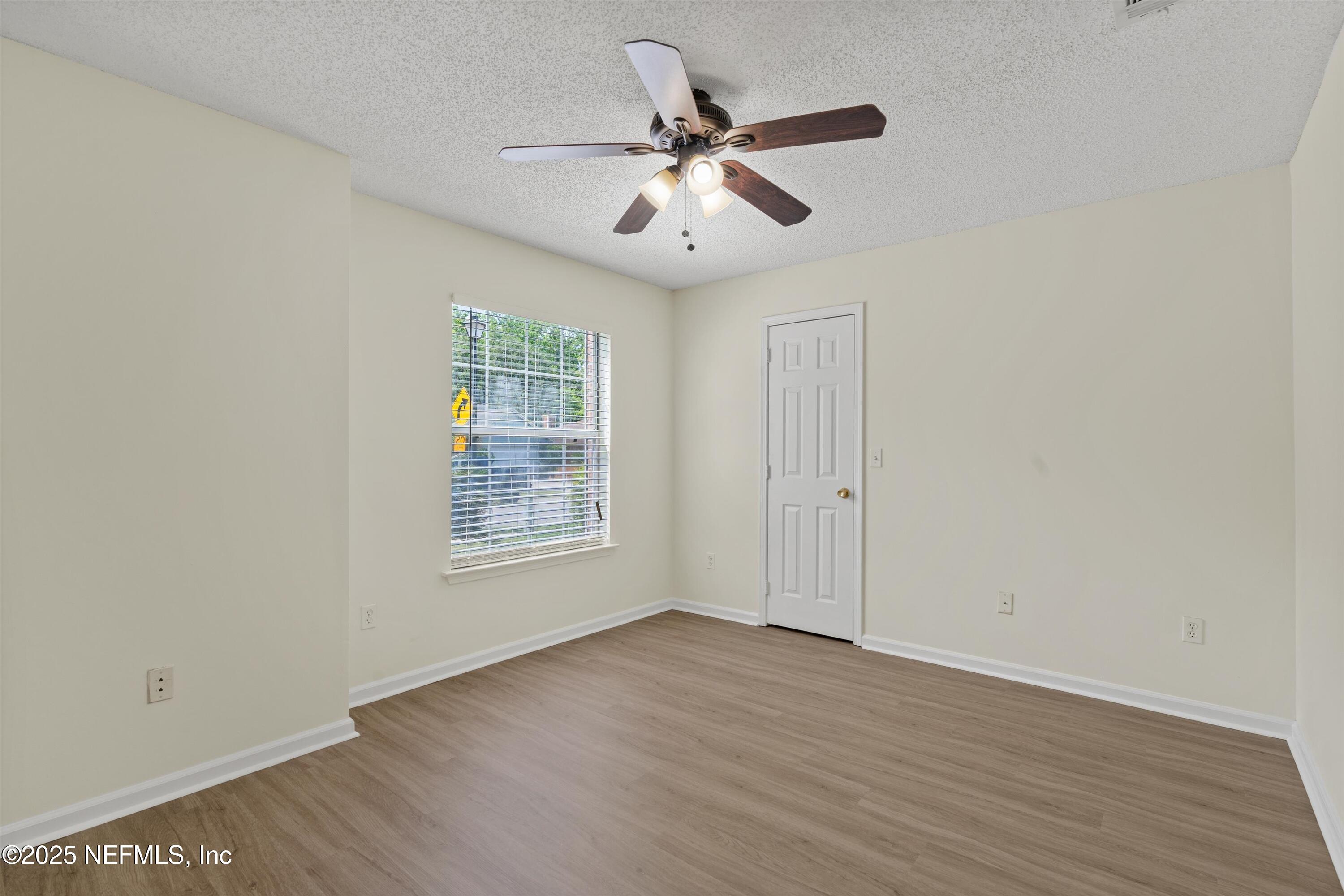 10713 Rutgers Road Jacksonville, FL 32218 - Photo 9 of 26 an empty room with wooden floor chandelier fan and windows