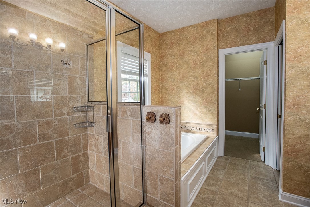 630 Rundle Street Lagrange, OH 44050 - Photo 20 of 49 Full bathroom with a shower stall, wallpapered walls, a spacious closet, a garden tub, and a textured ceiling