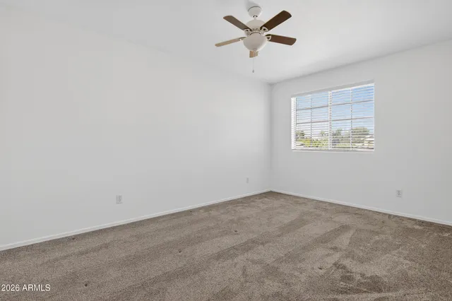 an empty room with a window and a fan