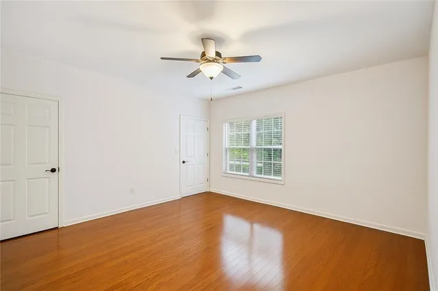 an empty room with wooden floor fan and windows