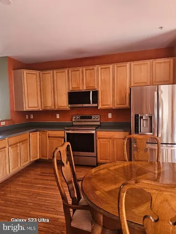 a kitchen with stainless steel appliances granite countertop a stove top oven a refrigerator a sink with a dining table and chairs