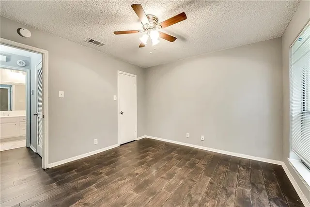 an empty room with wooden floor and a ceiling fan