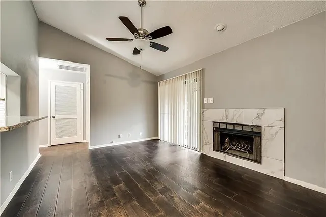 a view of an empty room with wooden floor fireplace and a window