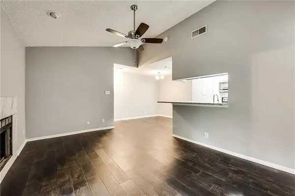 a view of an empty room with wooden floor and a ceiling fan