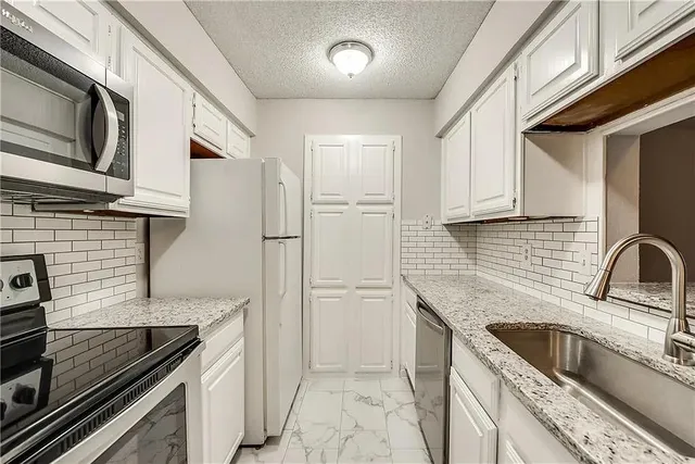 a kitchen with stainless steel appliances granite countertop a sink and a stove