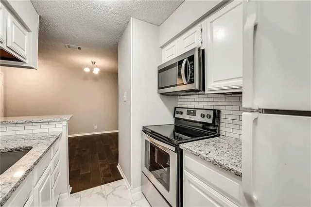 a kitchen with granite countertop cabinets stainless steel appliances and a counter space