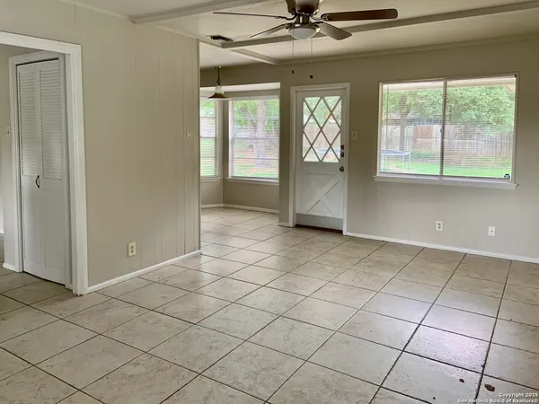 an empty room with windows and chandelier fan