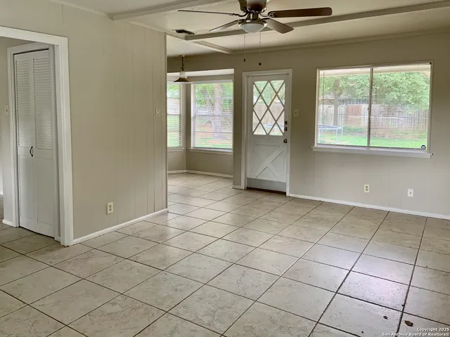 an empty room with windows and chandelier fan