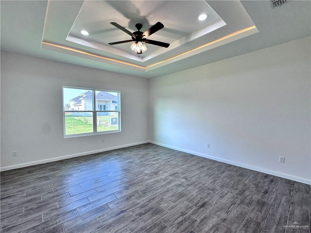 1100 Azalea Street Mission, TX 78573 - Photo 14 of 24 an empty room with wooden floor ceiling fan and windows