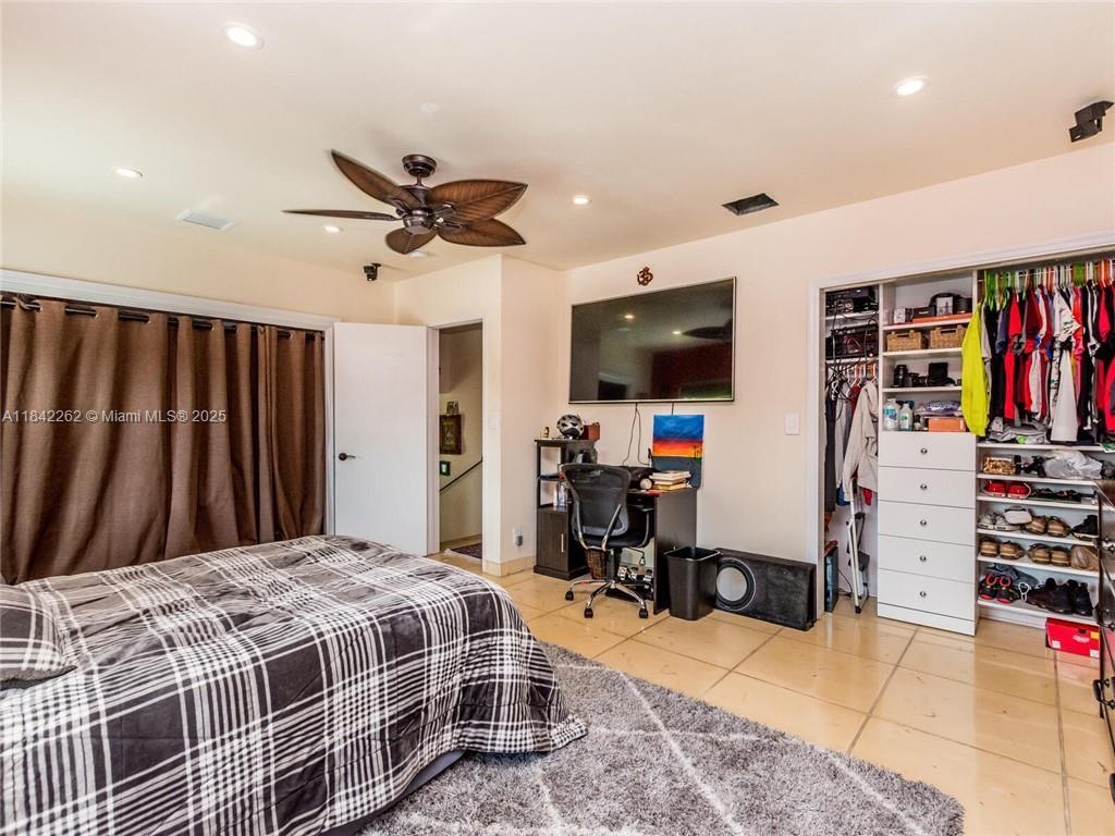 2616 Northeast 26th Avenue Lighthouse Point, FL 33064 - Photo 21 of 30 a bedroom with a bed a computer on a table and a flat screen tv