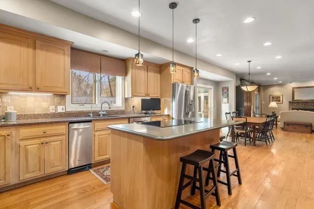 a kitchen with stainless steel appliances granite countertop table chairs sink and cabinets