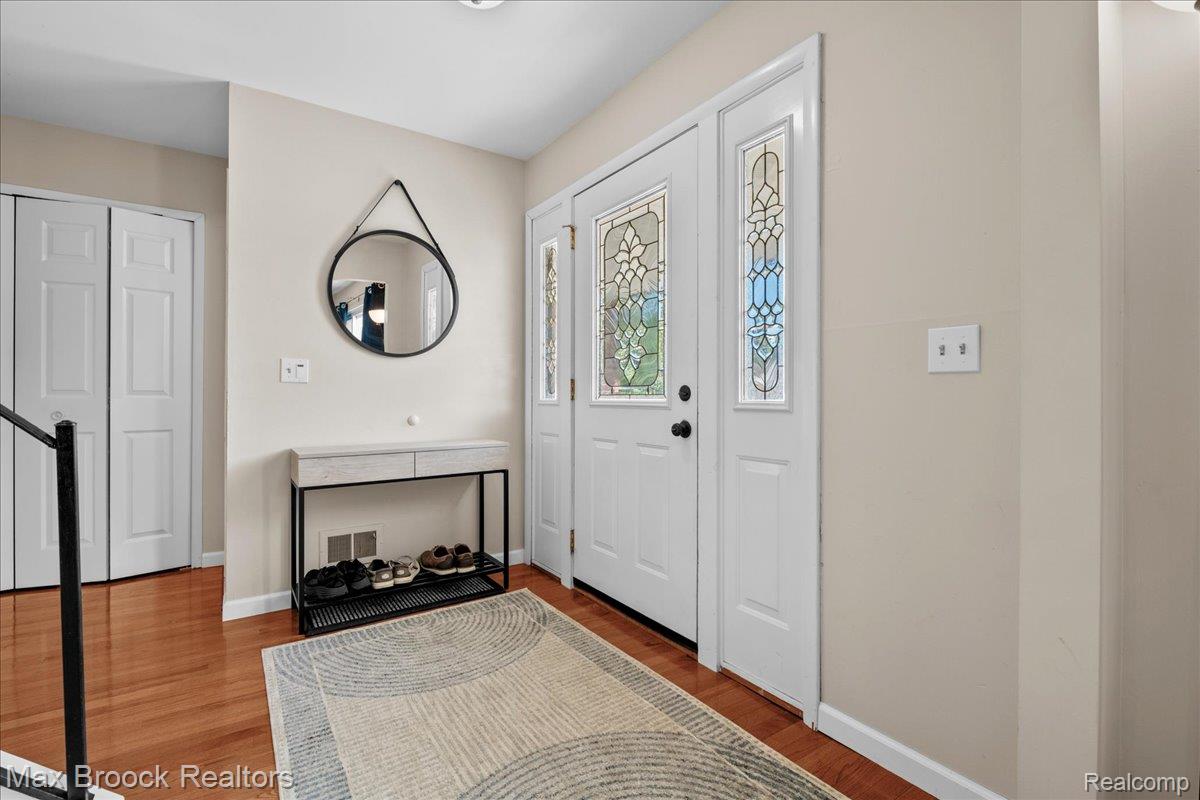42470 Bishop Road Canton, MI 48188 - Photo 3 of 37 Entryway featuring a solid door with decorative glass side panels, wood-finish flooring, and white bi-fold closet doors