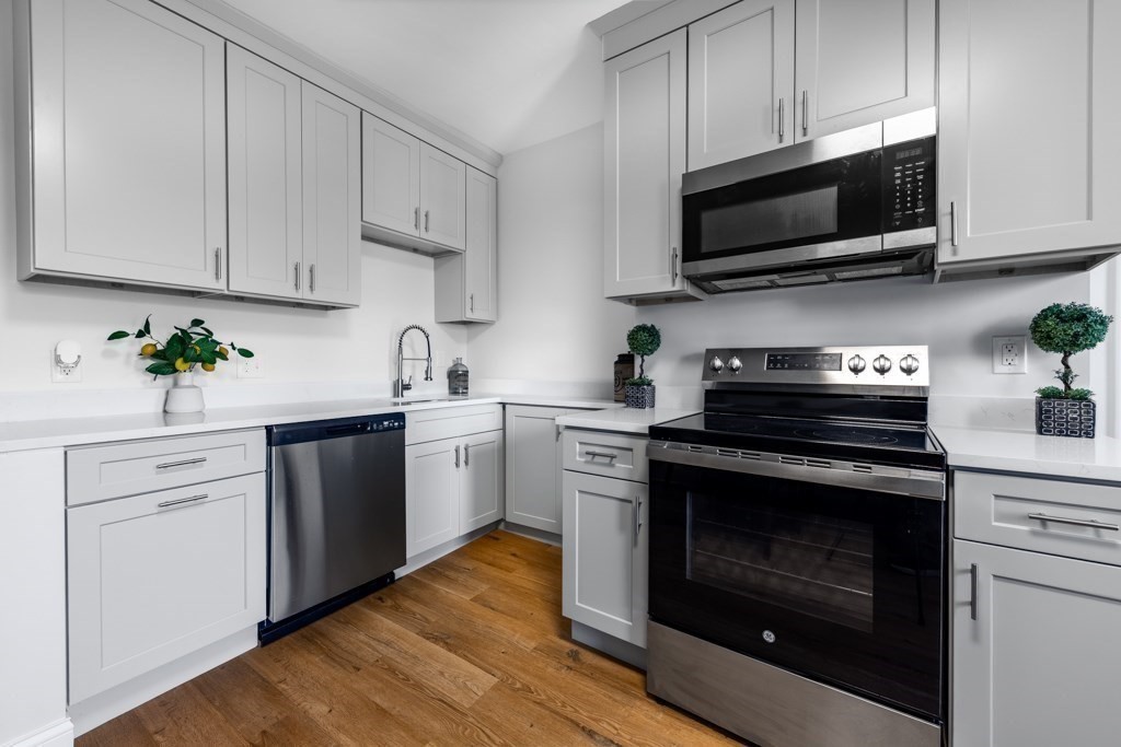 113 Regent Street Boston, MA 02119 - Photo 9 of 18 a kitchen with cabinets stainless steel appliances a sink and wooden floor