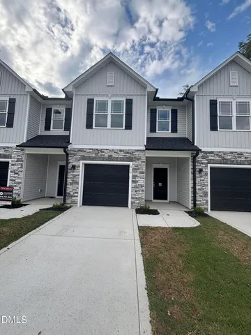 a front view of a house with yard and parking