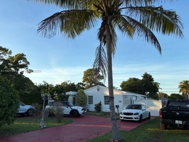 a car parked in front of white house with a yard