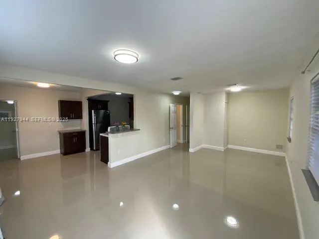 a view of an empty room and kitchen view