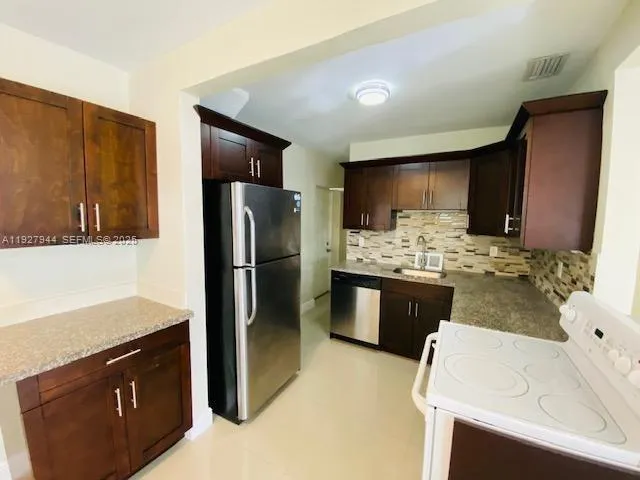 a kitchen with stainless steel appliances kitchen island granite countertop a sink stove and refrigerator