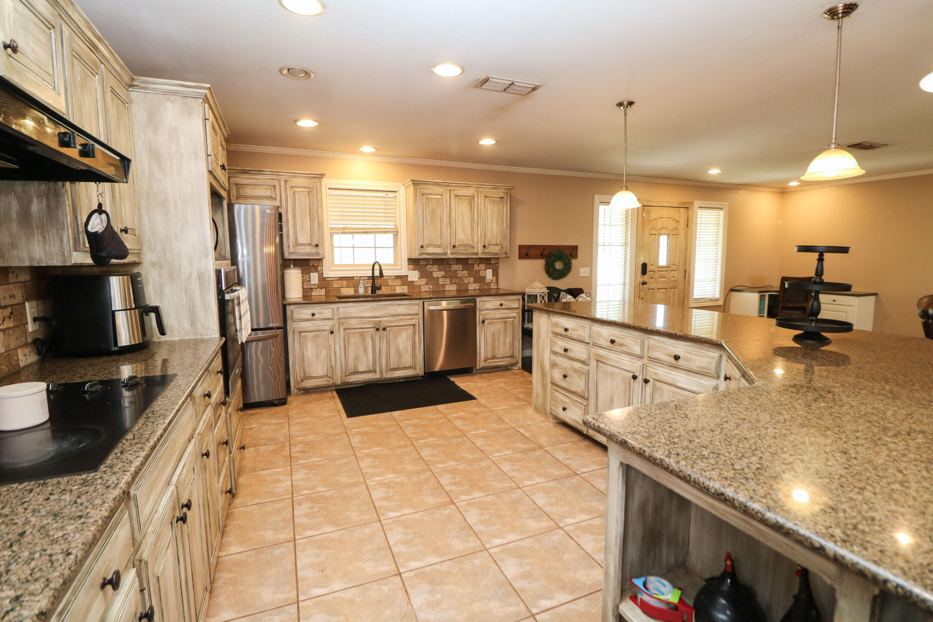 2401 Highway 385, Unit B Littlefield, TX 79339 - Photo 9 of 28 a large kitchen with kitchen island a large counter top space a sink stainless steel appliances and cabinets